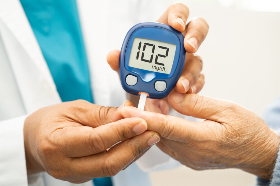 Ein Arzt überprüft bei einem Patienten mittels Messgerät den Blutzuckerspiegel.